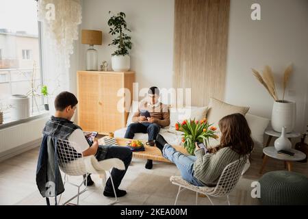 Siblings using phones and tablet at home Stock Photo