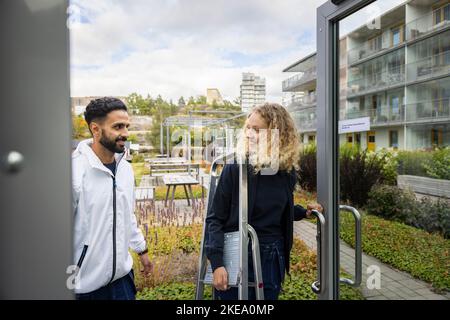Young technicians entering building with ladder Stock Photo