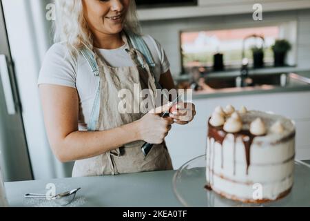 Woman in kitchen decorating cake Stock Photo