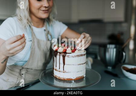 Woman in kitchen decorating cake Stock Photo