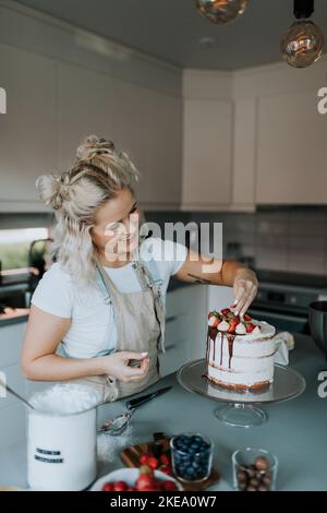 Woman in kitchen decorating cake Stock Photo