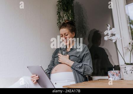 Pregnant woman using digital tablet Stock Photo