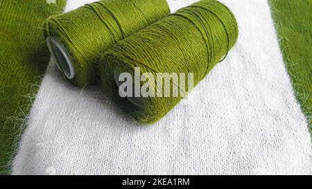 Handmade sweater. Knitted fabric from mink thread. White and olive color pattern. copy space. Stock Photo