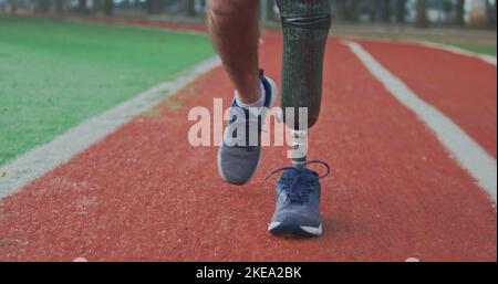 Front view of a disabled athlete man with prosthetic leg walking on running track Stock Photo