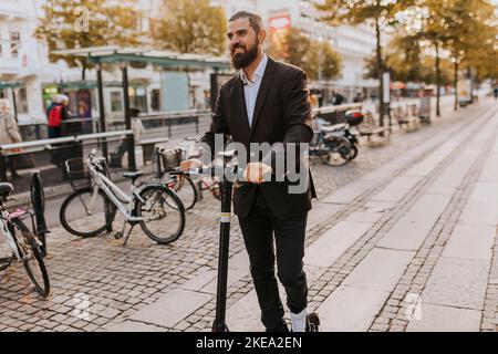 Smiling businessman using scooter Stock Photo