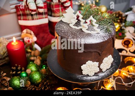 Christmas cake made of chocolate base with chocolate cream, decorated with Christmas trees and white chocolate snowflakes Stock Photo