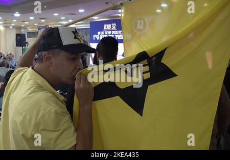 JERUSALEM, ISRAEL - NOVEMBER 10: A far right-wing activist kisses the flag of the outlawed Kach movement, a hard line Israeli militant group that advocates for the expulsion of Arabs from the biblical lands of Israel during a ceremony honoring late Jewish extremist leader Rabbi Meir Kahane, founder of the Kach party on November 10, 2022 in Jerusalem, Israel. Meir Kahane's party Kach, was barred from running for the Israeli parliament as the result of the extremist views the party promoted against Arabs. The United States, also outlawed the Kach movement and categorized it as a terrorist organi Stock Photo