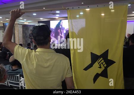 JERUSALEM, ISRAEL - NOVEMBER 10: A far right-wing activist holds up the flag of the outlawed Kach movement, a hard line Israeli militant group that advocates for the expulsion of Arabs from the biblical lands of Israel during a ceremony honoring late Jewish extremist leader Rabbi Meir Kahane, founder of the Kach party on November 10, 2022 in Jerusalem, Israel. Meir Kahane's party Kach, was barred from running for the Israeli parliament as the result of the extremist views the party promoted against Arabs. The United States, also outlawed the Kach movement and categorized it as a terrorist orga Stock Photo