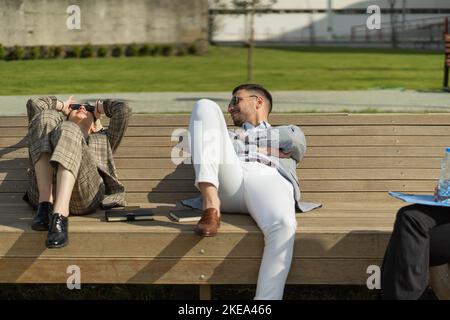 Three business co-workers are relaxing and talking about the business Stock Photo