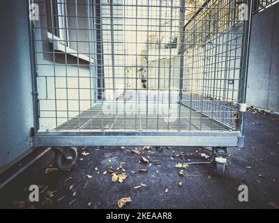 Empty iron-barred box on wheels outside a buidling Stock Photo