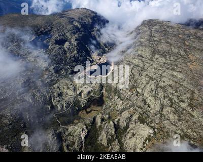 Aerial drone view of lakes in Serra da Estrela, Portugal with clouds above and fog passing. Travel and adventure. Nomad life. Hiking lifestyle. Stock Photo