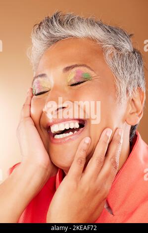 Happy, color and senior woman with makeup standing in a studio with colorful, trendy and edgy cosmetics. Happiness, smile and elderly lady with a Stock Photo