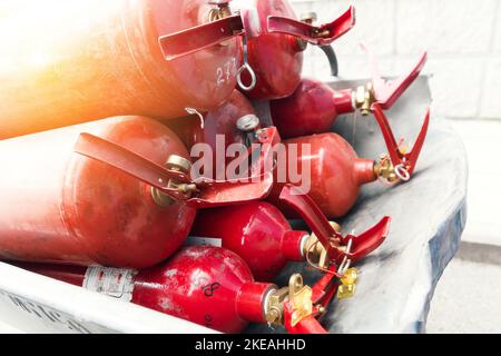 Many red fire extinguishers are lying in stack. Fire extinguishing equipment. Distribution of fire extinguishers for extinguishing fires.. Stock Photo