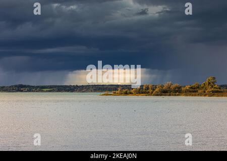 sun breaks through clouds during storm with heavy rain, Germany, Bavaria, Lake Chiemsee Stock Photo