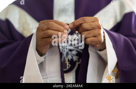 Priest, pastor and man hands with rosary with cross in church, prayer and catholic worship, praying or spiritual respect. Christian preacher, faith Stock Photo