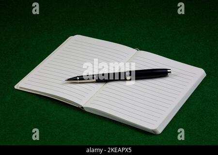 Rollerball pen and open notebook on a felt table cover Stock Photo