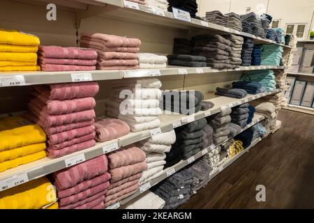 Colourful folded new towels on shelves at a homeware retail shop in Norwich Stock Photo