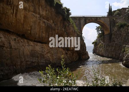 A view of the sea enters the fjord at Fiordo di Furore on the Amalfi Coast, Italy and a stone bridge connects rocky mountains Stock Photo