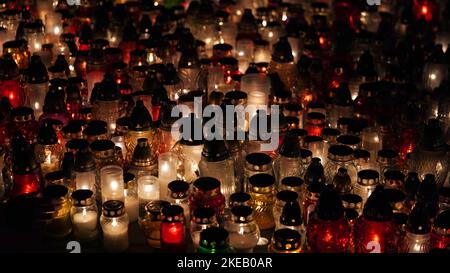 Lot of burning candles at night in cemetery.Glass inextinguishable lamps for cemetery.Day of remembrance and mourning for the dead.All Saints' Day.Com Stock Photo