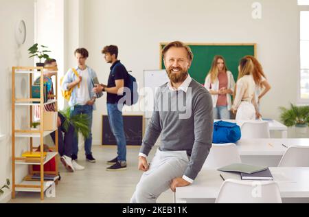 Portrait of a cheerful man who works as a school teacher standing in the classroom Stock Photo