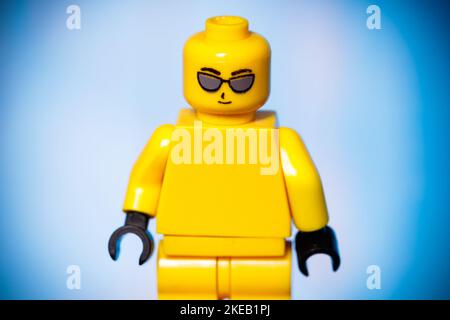 yellow lego figurine with joy on his face on a blue background. High quality photo Stock Photo