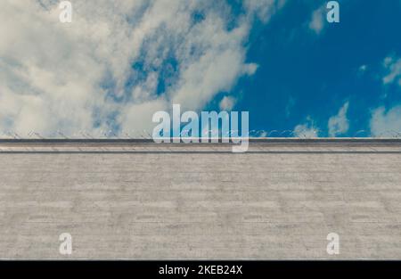 A massively high concrete security boundary wall topped with barbed ...