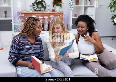African women and one European woman read books together on Christmas Day. Stock Photo