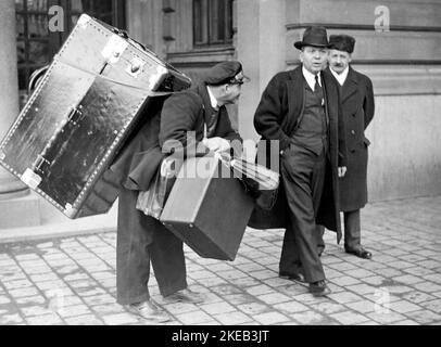 In the 1930s. Nobel chemistry prize laureates Harold Clayton Urey, 1893-1981. American. Pictured when arriving to Stockholm by train and he is seen on the right beside the man carrying all of his luggage. A very large case is seen on his back. Sweden 1934. Stock Photo