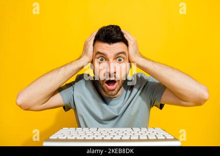 Closeup photo of young crazy smart it developer excited touching head unexpected bad news inflation economics use keyboard isolated on yellow color Stock Photo