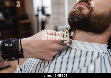 partial view of barber trimming neck of bearded man with hair clipper in barbershop,stock image Stock Photo