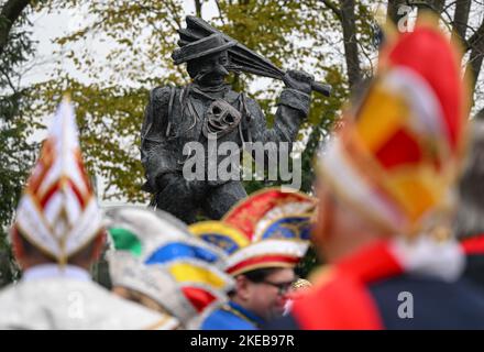 Hessen, Frankfurt/Main: 11 November 2022,  Carnivalists celebrate the return of their carnival symbol, the Urnarren, on 11.11. at H.P.-Müller-Platz in the Frankfurt district of Heddernheim, colloquially known as 'Klaa Paris'. The Urnarr is a gift from Lurgi AG for the 150th year of the Klaa Paris carnival and has stood at the subway station since 1989. It was dismantled a few weeks ago for repair and cleaning. Photo: Arne Dedert/dpa Stock Photo