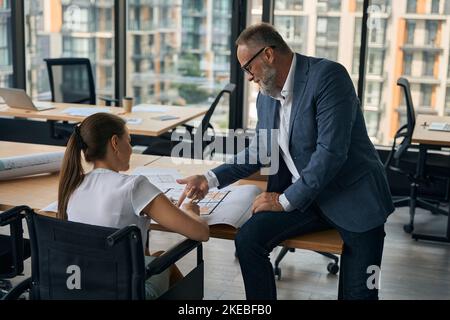 Joyful boss during meeting with female assistant in wheelchair Stock Photo
