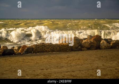 Amazing view to autumn stormy sea, big wave and splashing water on stone in nice illumination. Heraklion pier, Crete. Stock Photo