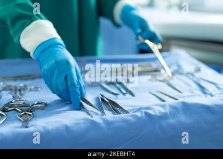 Midsection of surgical tech placing surgical tools on table in ...