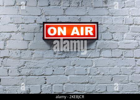a red on air sign against a white brick wall Stock Photo