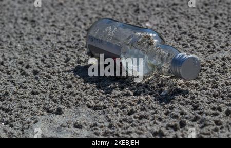 A glass bottle on the sand. Discarded glass bottle lying on sandy beach. Stock Photo