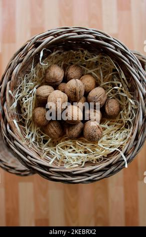 Whole Walnuts In A Wood Shavings Inside A Wicker Basket On A Wooden Planks Background For Vertical Story Stock Photo