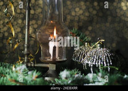 Lantern with burning candle and Christmas decorations on wooden table.  Golden bokeh background Stock Photo