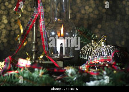 Lantern with burning candle and Christmas decorations on wooden table.  Golden bokeh background Stock Photo