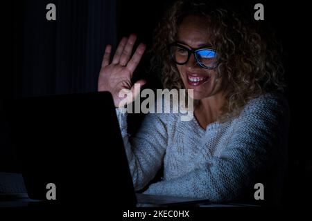 Front view of female employee speak talk on video call with diverse colleagues on online event briefing. Woman worker have group conference with coworkers on modern laptop at home at night. Stock Photo
