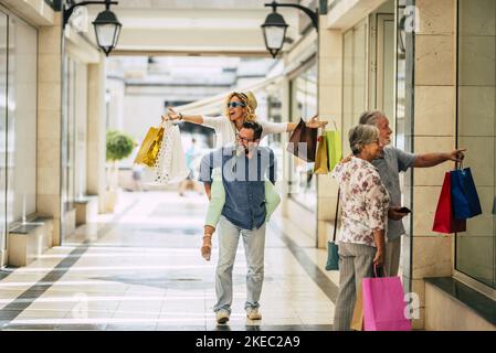 group of four people and family go shopping together holding a lot of shopping bags after buy it - black friday or cyber monday and sales time Stock Photo