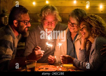 group of people celebrating the 2021 new year after a hard 2020 - bye 2020 concept - family enjoying and having fun together with sparklers at home eating pizza at dinner - christimas concept Stock Photo
