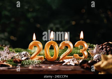 Holiday background Happy New Year 2023. Numbers of year 2023 made by gold burning candles on bokeh festive sparkling background. celebrating New Year Stock Photo