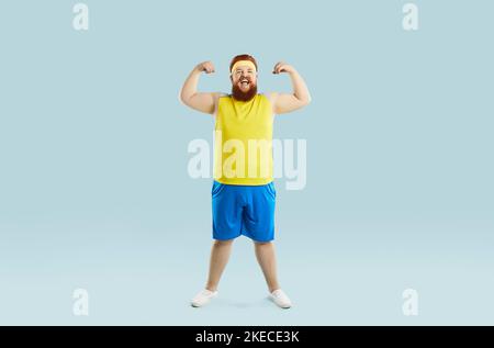 Funny chubby man smiling and flexing his arms during a fitness workout at the gym Stock Photo