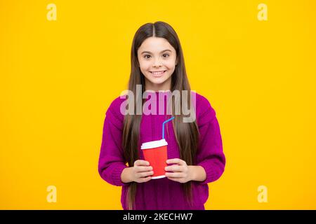 Teenage girl with take away cup of cappuccino coffee or tea. Child with takeaway cup on yellow background, morning drink beverage. Stock Photo