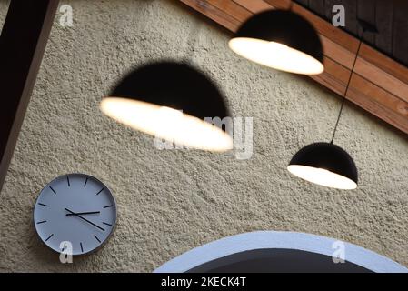Clock on the Wall Under Three Lamps Indoors Stock Photo