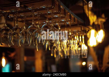 A closeup of empty wine glasses hanging from a hanging rack Stock Photo