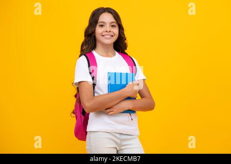 Back to school. Teenager school girl hold book and copybook ready to learn. School children with school bag on isolated yellow studio background. Stock Photo