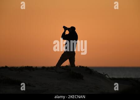 Photographer at work on the beach in Coronado, California at sunset Stock Photo