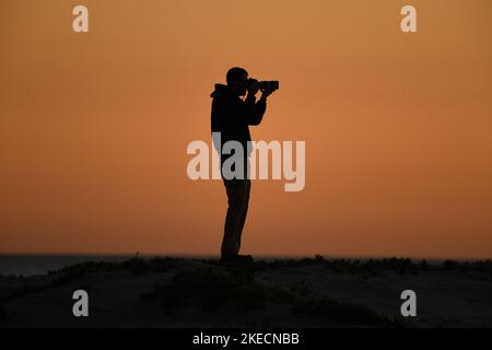 Photographer at work on the beach in Coronado, California at sunset Stock Photo